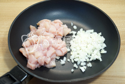 На сковороде с двумя столовыми ложками растительного масла обжарить мелко нашинкованный лук и кубиками нарезанное куриное филе 3-5 минут.