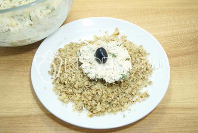 Ложкой набрать салатную массу в середину уложить маслину, сформировать шарик и обвалять в орехах.