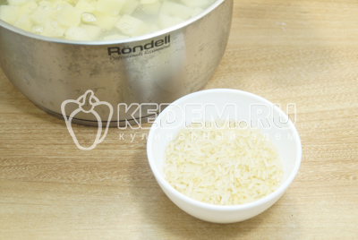 Добавить картофель в кастрюлю, добавить рис и поставить варить.