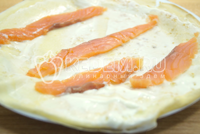 Смазать блин сливочным сыром и выложить кусочками нерезаную рыбу.