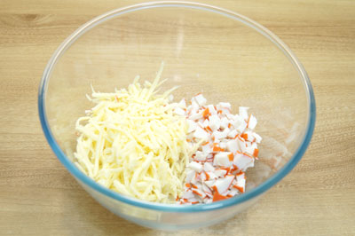 В миску нарезать крабовые палочки и натереть сыр на терке.