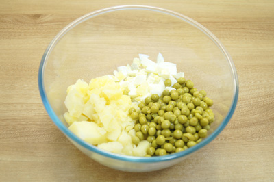 В миску нарезать кубиками картофель и яйца, добавить горошек.
