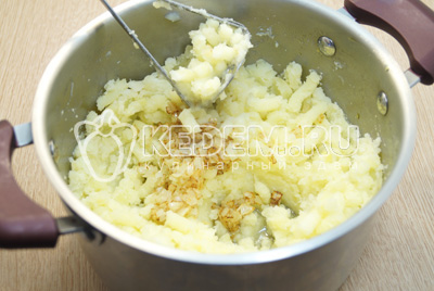 Добавить лук с маслом в кастрюлю и еще раз хорошо размять картофель в пюре.