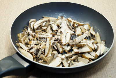 Нарезать соломкой грибы, лук мелко порубить, обжарить на сковороде с растительным маслом, 5 минут помешивая.