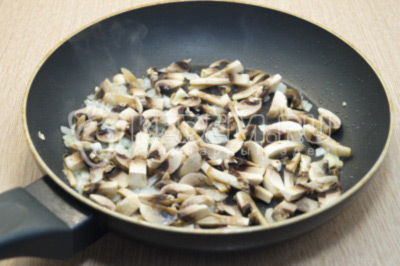 На сковороде с растительным маслом обжарить мелко нашинкованный лук и мелко нарезанные грибы. Готовить 2-3 минуты. Посолить.