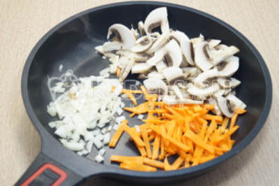На сковороде обжарить с растительным маслом мелко нашинкованный лук, соломкой нарезанную морковь и нарезанные грибы.