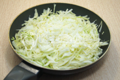 На сковороду с растительным маслом выложить нашинкованную капусту и лук. Обжаривать 10-12 минут помешивая.