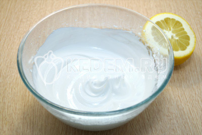 В миску отделить 2 белка от желтков, взбить с 100 грамм сахарной пудры и 3-4 каплями сока лимона.