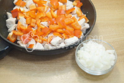 К куриному филе добавить кубиками нарезанный болгарский перец и мелко нашинкованный лук. Готовить 3-4 минуты.