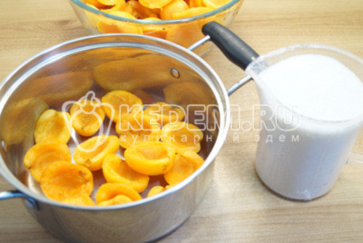 В кастрюлю выложить слой абрикосов и присыпать небольшим количеством сахара. Оставить 150 грамм сахара.