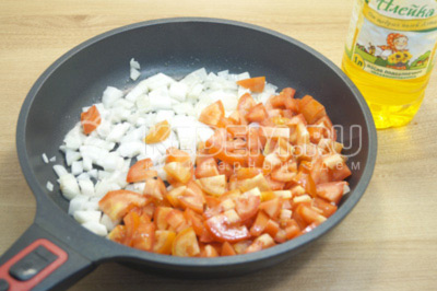 На сковороде разогреть натуральное нерафинированное подсолнечное масло и обжарить мелко нашинкованный лук и кубиками нарезанные помидоры, готовить 3-4 минуты.