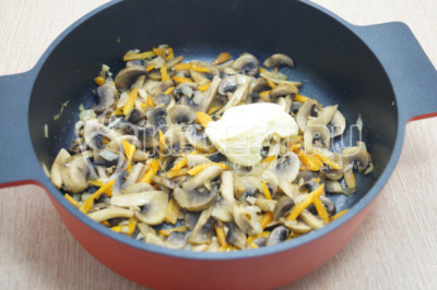 В сотейник с грибами добавить сливочное масло и посолить.