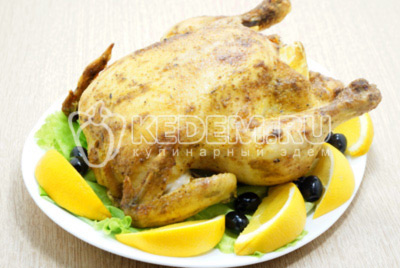 Готовую курицу выложить на блюдо. Украсить дольками свежего апельсина, зеленью и оливками.
