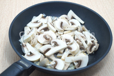 Добавить нарезанные грибы шампиньоны и готовить 3-4 минуты.