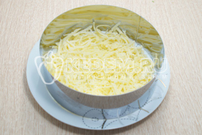 В сервировочном кольце нижним слоем выложить 100 г тертого сыра.