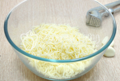 В миску с тертым сыром добавить прессованный или измельченный чеснок.