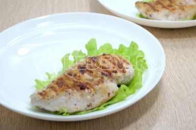 На тарелки выложить листья салата и куриное филе.