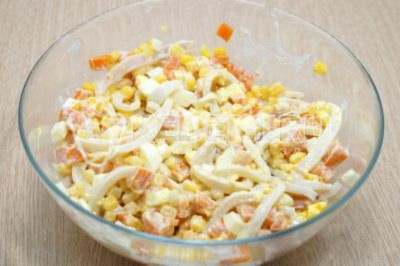 Перемешать и посолить по вкусу салат из кальмаров с кукурузой и яйцом.