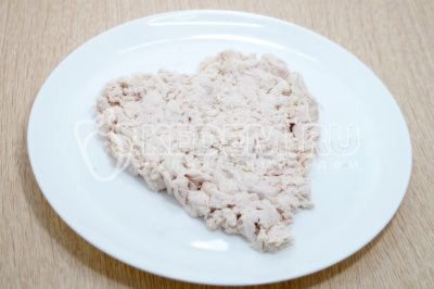 На блюдо выложить мелко нарезанное куриное филе в виде сердца.