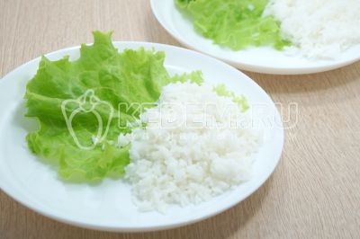 На блюдо выложить листья салата и рис.