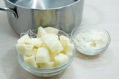 В кастрюлю влить 2 литра воды и добавить картофель нарезанный кубиками и мелко нашинкованную луковицу. Варить 10 минут.