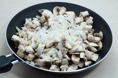 На сковороде с маслом обжарить нарезанные грибы с мелко нашинкованным луком.
