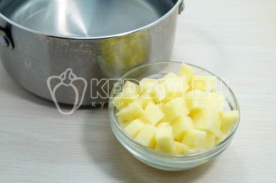 В кастрюле вскипятить 2 литра воды, добавить 2 нарезанных кубиками картофелины.