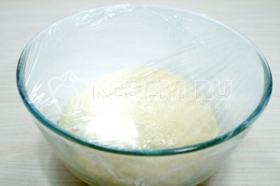 Затянуть миску пищевой пленкой и оставить тесто для пирожков в теплом месте на 40-60 минут.