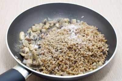 Добавить отварную гречку в обжаренные грибы. Добавить 1/4 чайной ложки соли и черный молотый перец по вкусу.