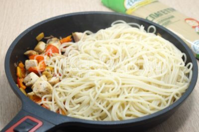Добавить отварные спагетти в сковороду.