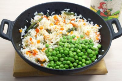 100 грамм зеленого горошка разморозить и добавить в сковороду к рису, обжарить 7-10 минут.