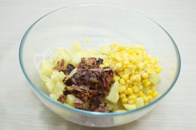К картофелю добавить нарезанный бекон и 100 грамм консервированной кукурузы.