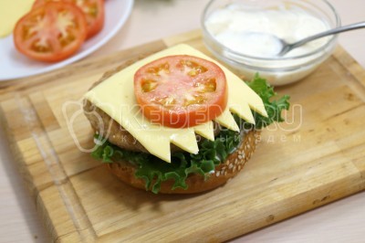 Выложить сверху котлеты ломтик сыра и кружок помидора.