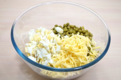 В миску добавить нарезанные кубиками отварные яйца и тертый сыр.