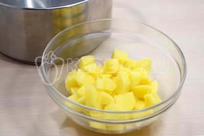 Нарезать картофель кубиками и выложить в кастрюлю, поставить на средний огонь.