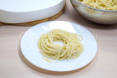 Из спагетти сформировать небольшие порционные гнезда и выложить в форму для запекания.