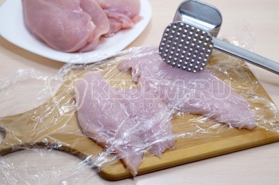 Накрыть куриное филе пищевой пленкой и отбить.