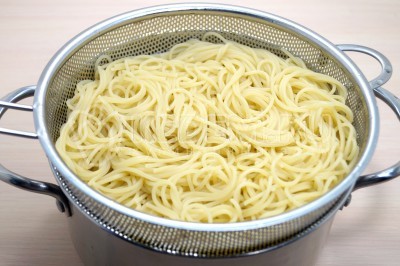 Откинуть спагетти на дуршлаг и дать воде стечь.
