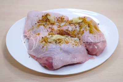 Натереть куриные бедра специями, солью и измельченным чесноком.