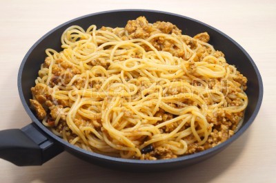 Добавить спагетти в сковороду к томатному соусу с фаршем и перемешать.