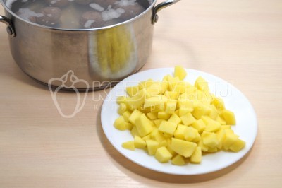 Добавить кубиками нарезанный картофель и варить вместе с фрикадельками 5-7 минут.