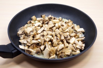 Нарезать150 грамм свежих шампиньонов кубиками и добавить к луку. Обжарить грибы с луком, помешивая, 4-5 минут. Посолить и поперчить по вкусу.