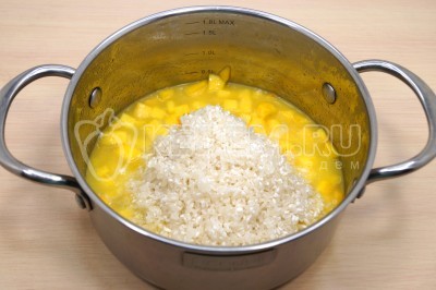 Добавить промытый рис в кастрюлю к тыкве.