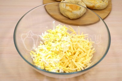 В миску на крупной терке натереть отварные яйца и 100 грамм твердого сыра.