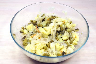 Хорошо перемешать салат с квашеной капустой и картофелем в миске. 