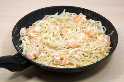 Добавить спагетти в сковороду к морепродуктам и перемешать. Держать на медленном огне 1-2 минуты и снять с плиты сковороду.