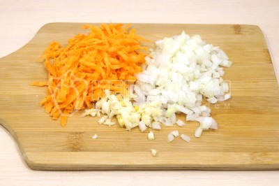 Чтобы приготовить суп с куриными фрикадельками, нужно луковицу мелко нашинковать. Морковь натереть на терке. 1 зубчик чеснока измельчить.