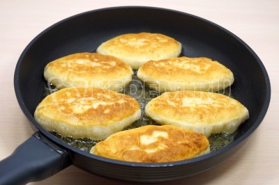 Перевернуть и жарить быстрые пирожки на кефире с яйцом и зеленым луком еще 2 минуты до золотистой корочки.