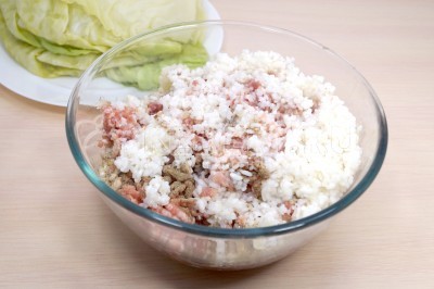 Добавить в миску к фаршу отварной рис, 1 чайную ложку соли и черный молотый перец по вкусу.