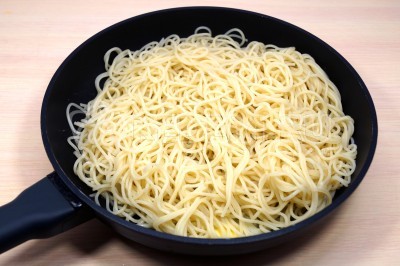 Добавить отварные спагетти в сковороду и обжарить их 1-2 минуты.